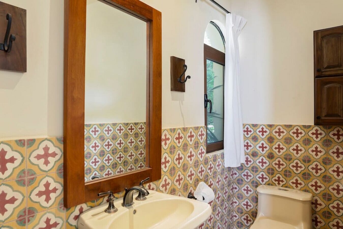 A bathroom with a sink, mirror, and toilet.
