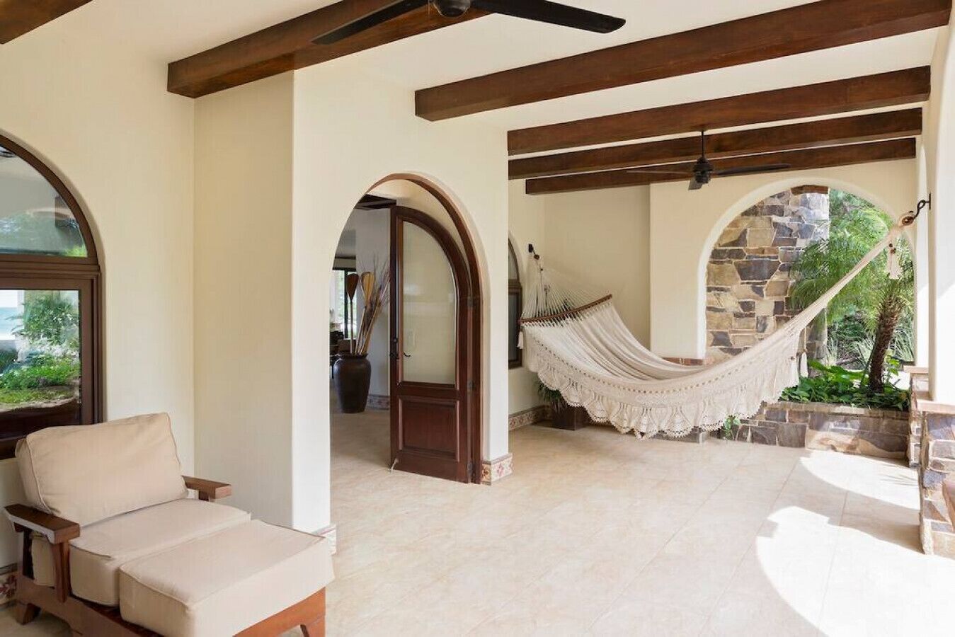 Un patio amplio con una hamaca, una silla acolchada y un muro de piedra.