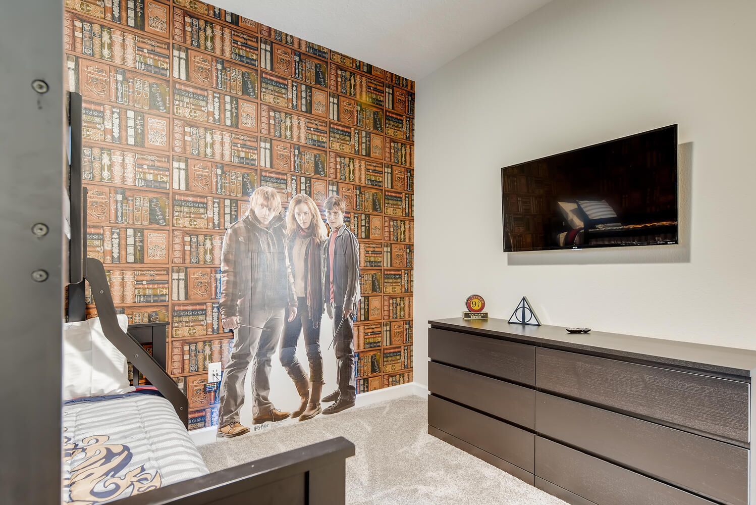 Un dormitorio con una pared de estanterías, un televisor de pantalla plana y un moderno aparador.