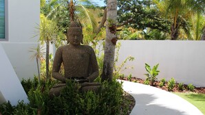 A Buddha statue surrounded by tropical plants and a white wall. - Palm Cottages - Entire Compound - Tropical Oasis (Vieques)