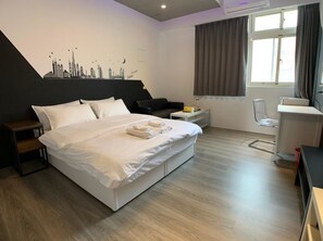 Una habitación de hotel moderna con una cama grande, un escritorio, una silla y un mural con el paisaje urbano en la pared.