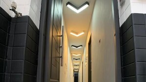 Un pasillo con flecha direccional en la alfombra, paredes blanco y negro y un moderno accesorio de iluminación en el techo.
