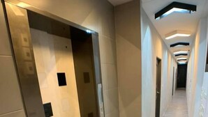 Un pasillo moderno con piso de tonos claros, pared con diseños geométricos e iluminación empotrada.