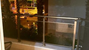 A balcony with a metal railing, a view of a street with cars and buildings, and a tiled floor. - Arkin Daire 1 bedroom (Alanya)