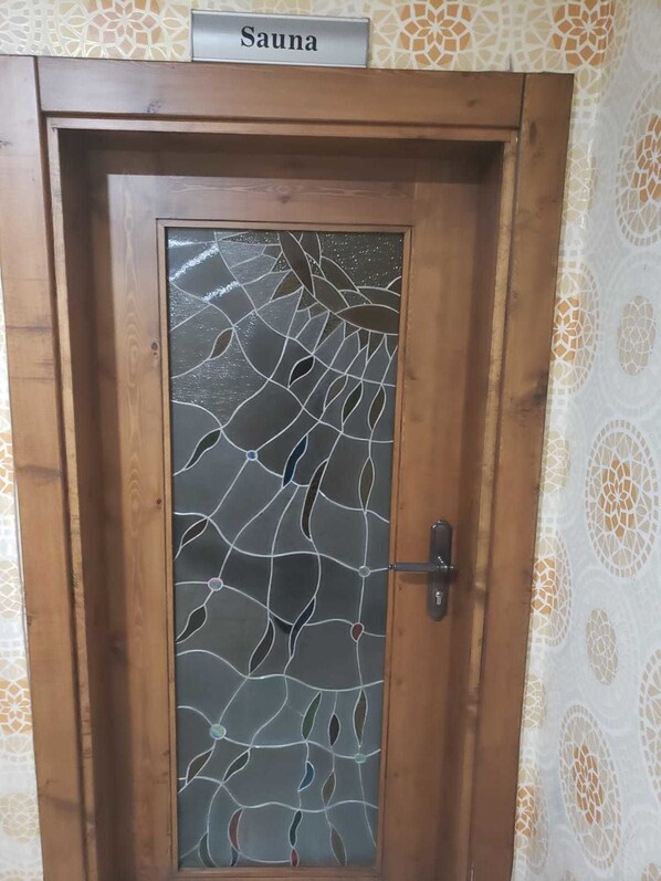 Una puerta de madera con un panel de vidrio satinado que presenta un diseño de hojas.
