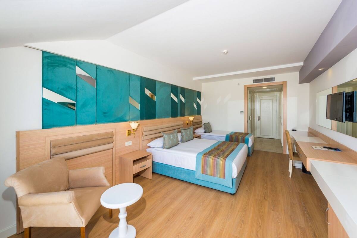 A hotel room with two beds, a sofa, a small table, and a TV.