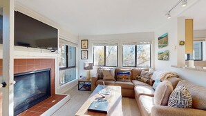 A living room with a fireplace, a large TV, and a sofa with decorative pillows.
