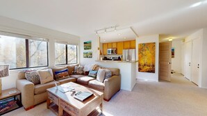 A spacious living area with a sofa set, a coffee table, and a kitchen area with modern appliances.