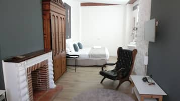 Un dormitorio con chimenea, una cama, un sillón y una mesita.