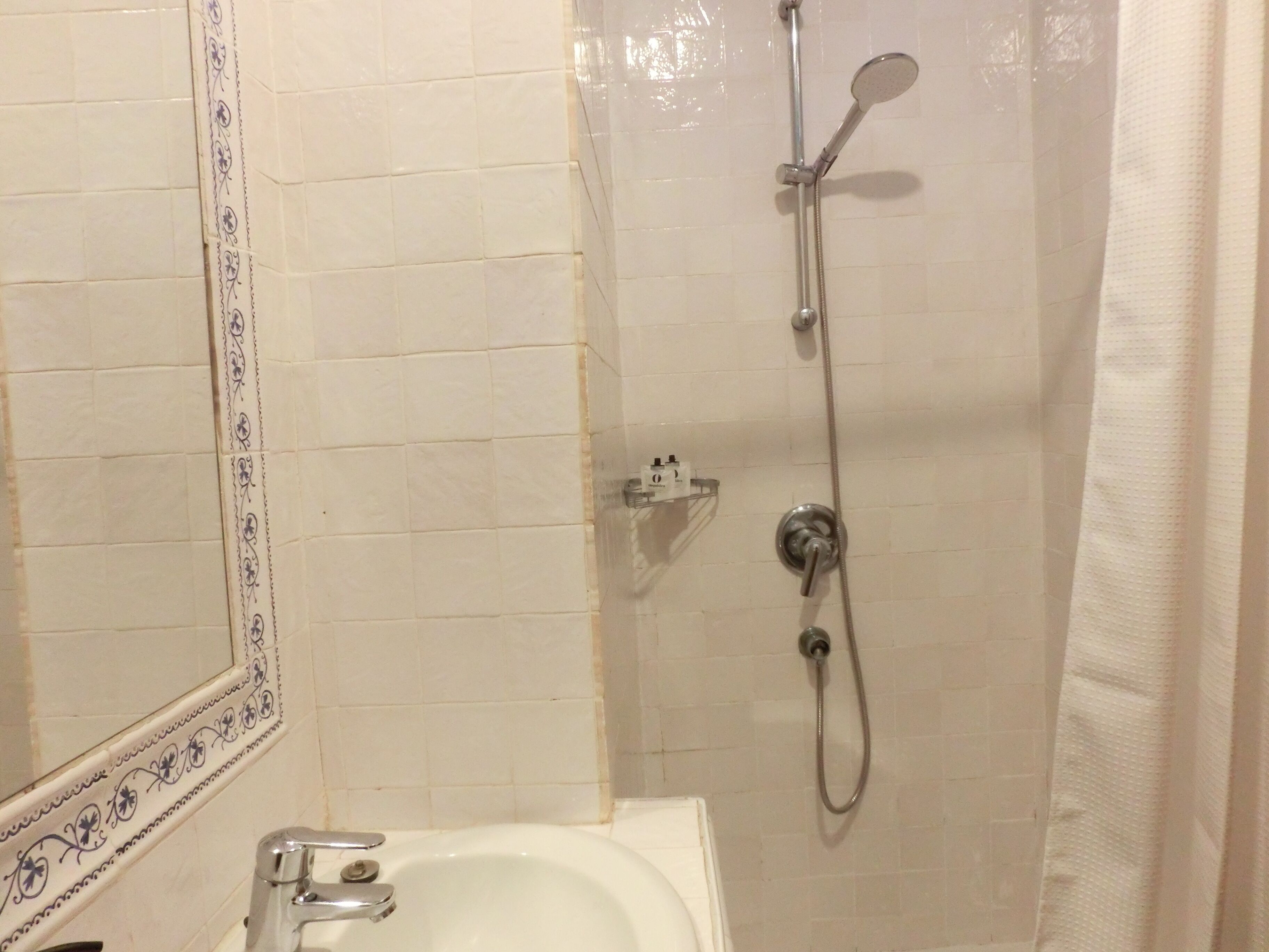 Une salle de bain avec une baignoire blanche, une douche équipée d’un pommeau de douche à main et un porte-serviettes fixé au mur.