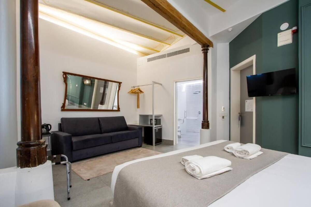Een hotelkamer met een bed, een bank, een televisie en een spiegel.