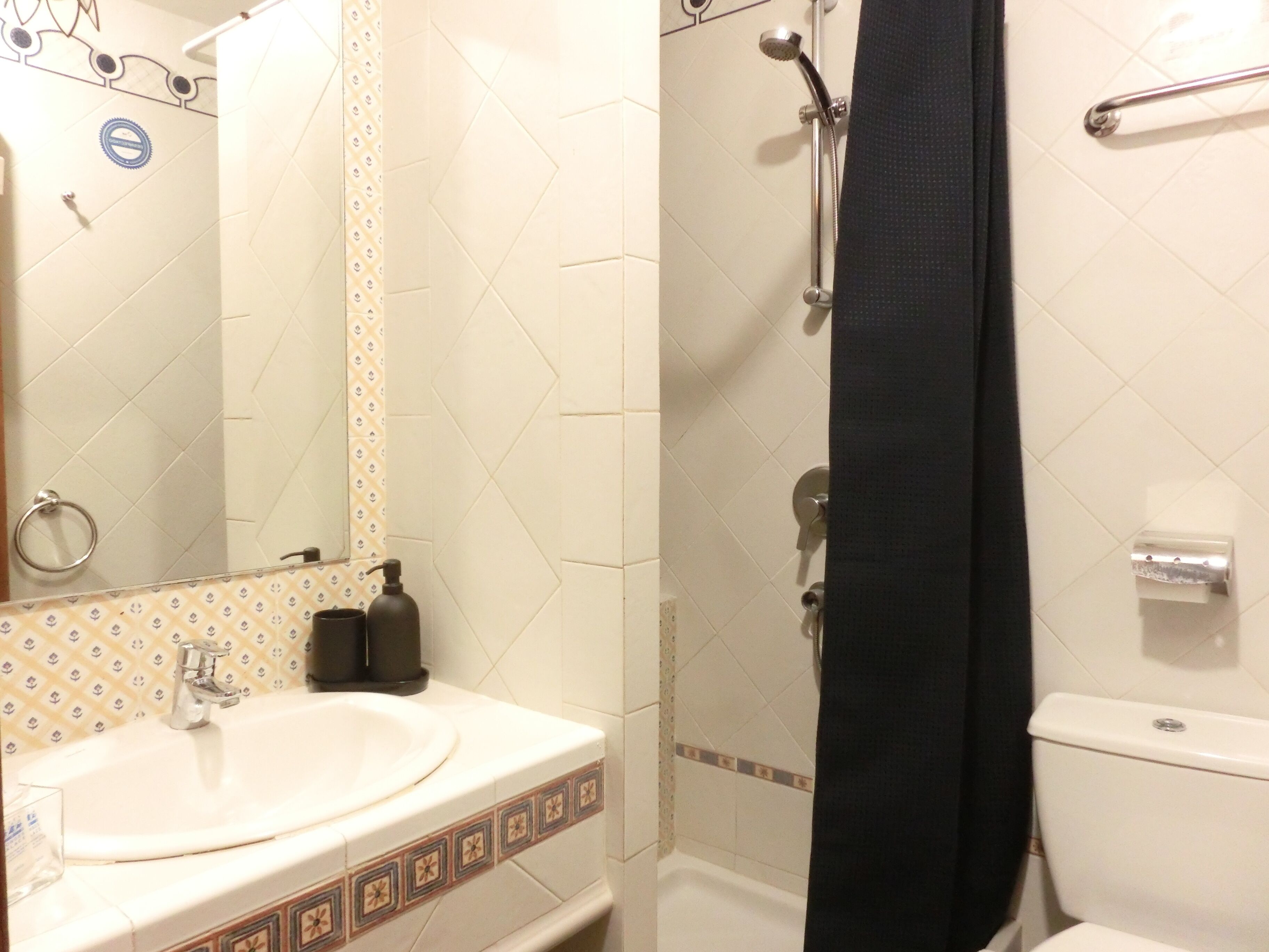 Een badkamer met een wastafel, spiegel, douche en toilet.