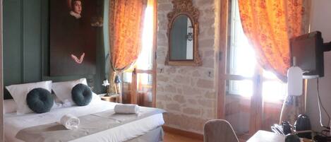 A hotel room with a bed, a desk, a chair, a telephone, and a mirror.