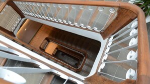 Een houten trap met een metalen leuning en een klein houten bankje onderaan.