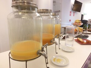 Een drankstation met verschillende tappunten, een schaal met fruit en een tafel met borden en bestek.