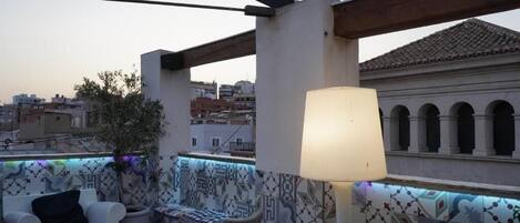 Une terrasse sur le toit, dotée d’un espace salon, d’une lampe et de carreaux décorés.