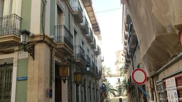 Eine schmale Straße, gesäumt von Gebäuden mit Balkonen und schmiedeeisernen Geländern. Ein Schild zeigt 'Calle Monjas'.