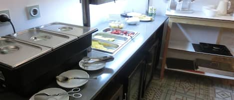 Montaje de bufé con varios dispensadores de alimentos, bandejas de servicio y cubiertos.