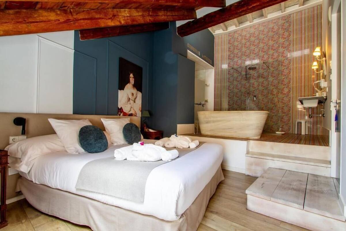 Een slaapkamer met een groot bed, een douche en een badkamer met een behang.