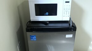 Een koelkast van roestvrij staal met een digitaal scherm en een ingebouwde magnetron, bevestigd aan een betegelde muur.