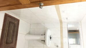 Een badkamer met een wit wastafelmeubel, een bruin kleed en een houten plafond.