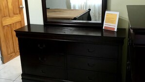Een donkere houten dressoir met een grote spiegel en een bordje erboven.