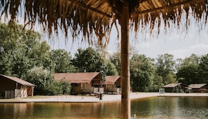 Alojamiento frente al lago con cabañas de madera y una estructura de techo de paja.