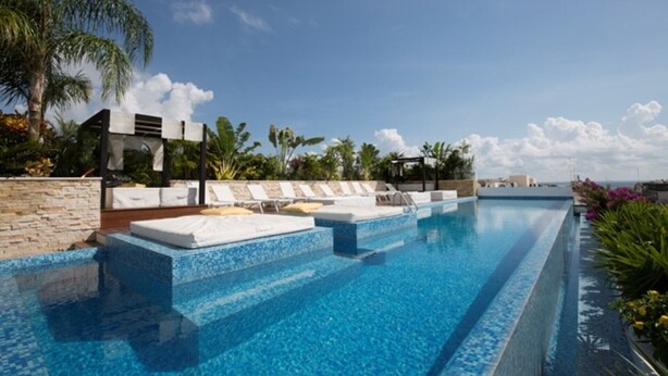Una piscina con sillones de descanso y una pared de piedra.