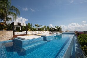 Una piscina con sillones de descanso y una pared de piedra.