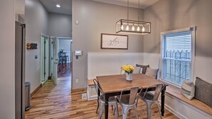 A dining area with a wooden table, metal chairs, a hanging light fixture, and a window with blinds. - Updated Indianapolis Home, Walk to Lucas Oil! (Indianapolis)