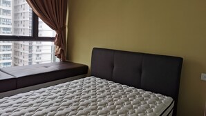 Quarto com cama, janela com cortinas e vista para edifícios altos.