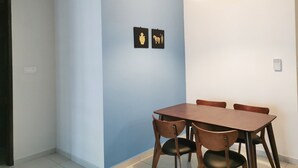 Uma  área de refeições com uma mesa, cadeiras, uma luminária pendente e duas imagens penduradas na parede.