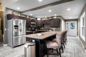 A modern kitchen with a central island, stainless steel appliances, and dark wood cabinets. - Schuss Mountain Chalet (Mancelona)