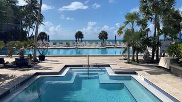 Une piscine avec vue sur l’océan, entourée de palmiers et de chaises longues.
