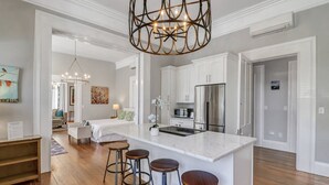 A modern kitchen with a central island, bar stools, and stainless steel appliances. - Mayor's luxury 1869 historic home for 4 on the square! (Savannah)