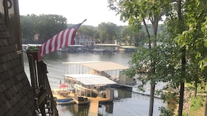 A riverside view with a dock, boats, and a flag. - Lakefront home near Margaritaville  w/lrg private dock -Kelly’s Place (Osage beach)