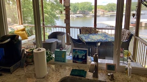A cozy room with a view of a river, a dining area with a table and chairs, and a kitchen counter with various items. - Lakefront home near Margaritaville  w/lrg private dock -Kelly’s Place (Osage beach)