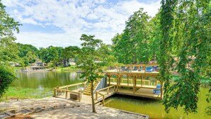Un muelle de madera se extiende sobre un lago tranquilo, rodeado de abundante vegetación y árboles.