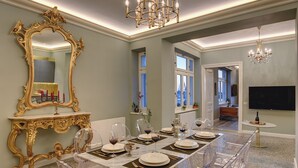 A dining area with a large ornate mirror, a chandelier, and a table set for six with clear chairs. - Arena & Seaview Luxury Residence (Pula)