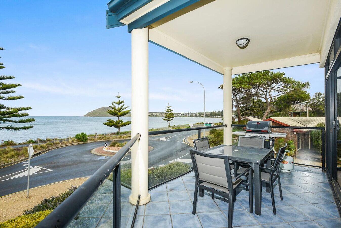 Un balcon avec vue sur la mer, un espace barbecue et un sol carrelé.