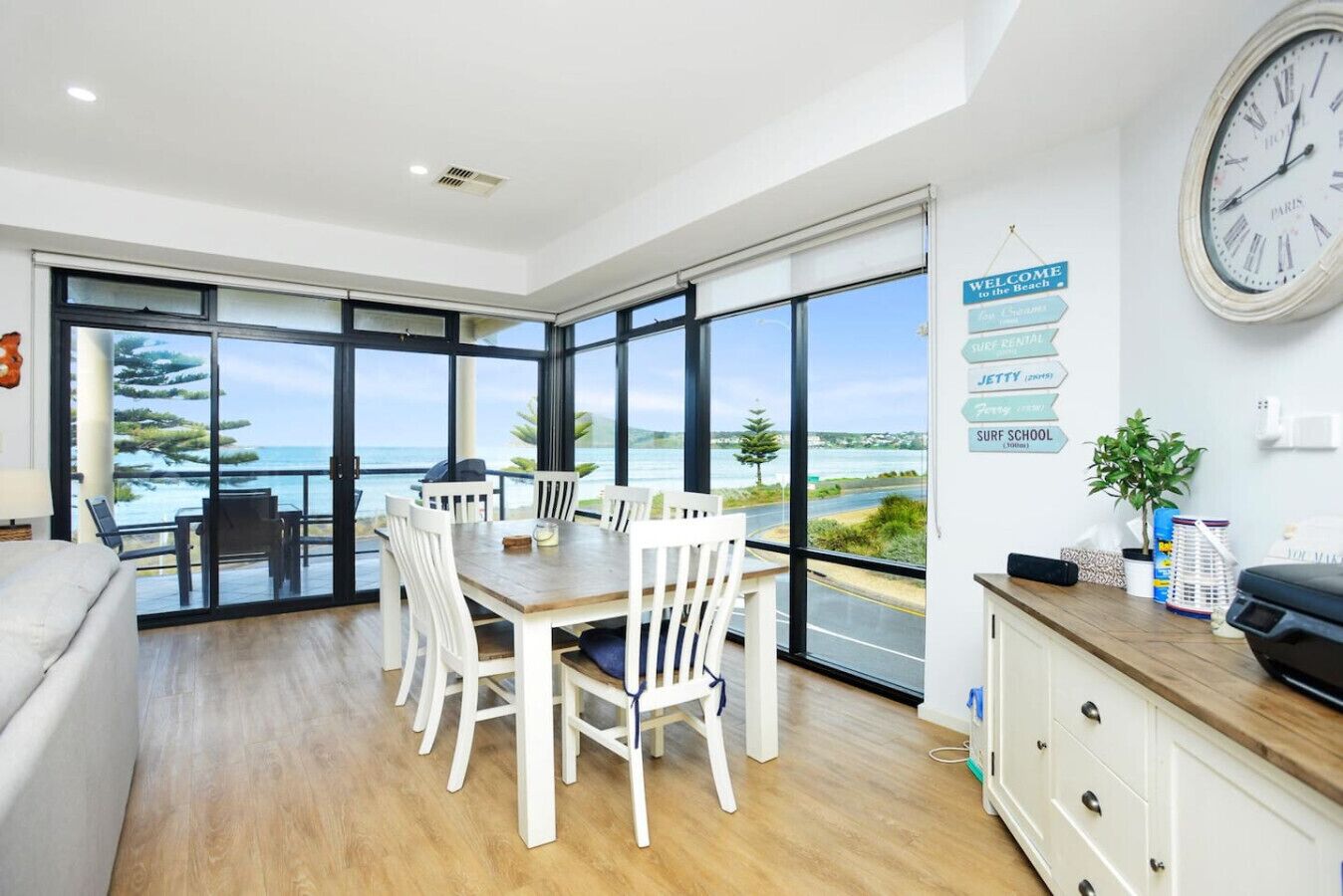 A modern dining area with a view of the sea, a clock, and directional signs.