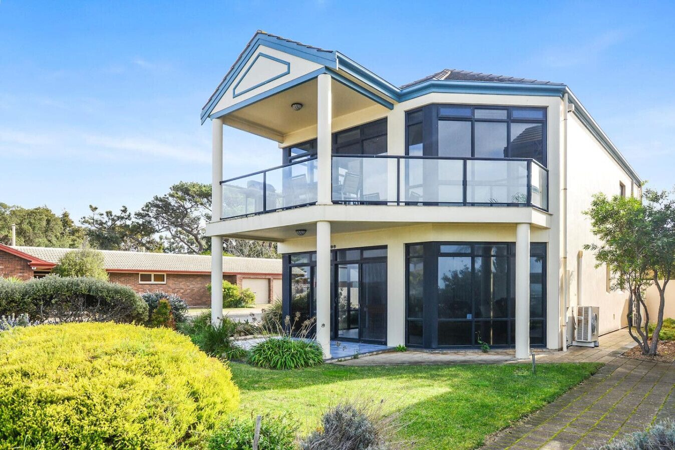A two-story house with a balcony, large windows, and a well-maintained garden.
