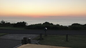 A wooden deck with a view of the ocean at sunset.
