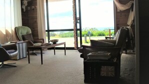 A cozy living room with a view of the sea, furnished with a sofa, armchair, and a small table.