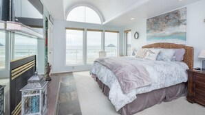Un dormitorio con una cama grande, vistas al océano y un balcón con barandilla.