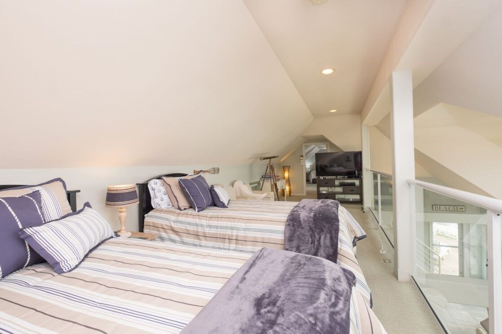 Een slaapkamer met twee bedden, een televisie en een balkon.