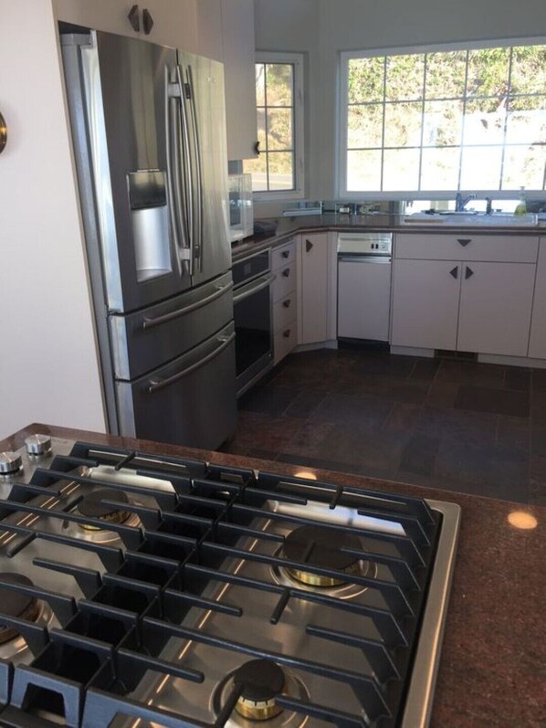 A modern kitchen with stainless steel appliances, a gas stove, and white cabinetry. - Take A Peek...at This Lovely Beach Front Home (Oceanside)