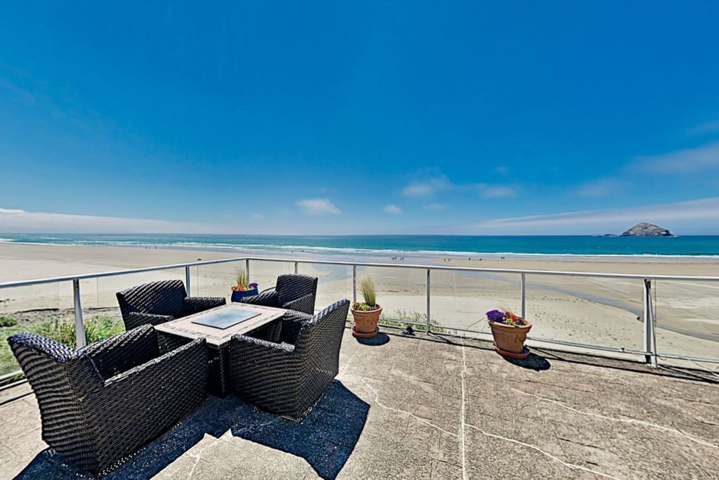 Un balcon doté de meubles en osier et de plantes en pot, offrant une vue sur la plage.