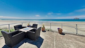 Un balcón con mobiliario de mimbre y plantas en macetas con vista a la playa.
