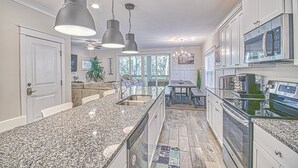 Una cocina moderna con encimeras de granito, electrodomésticos de acero inoxidable e iluminación colgante.